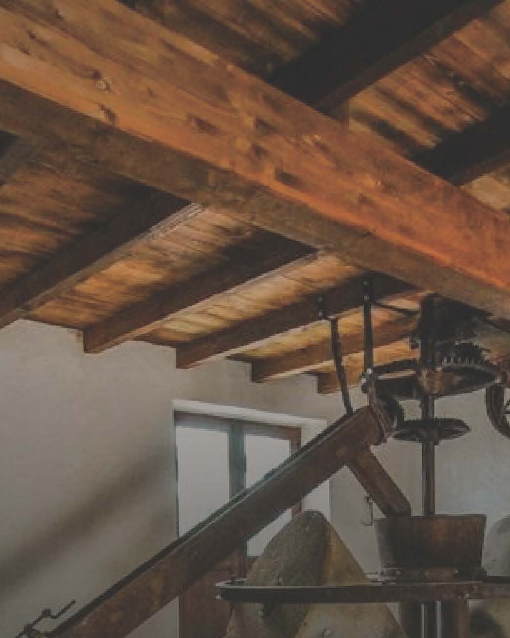 The original press machinery under the restored timber ceiling of a historic Andalusian oil mill