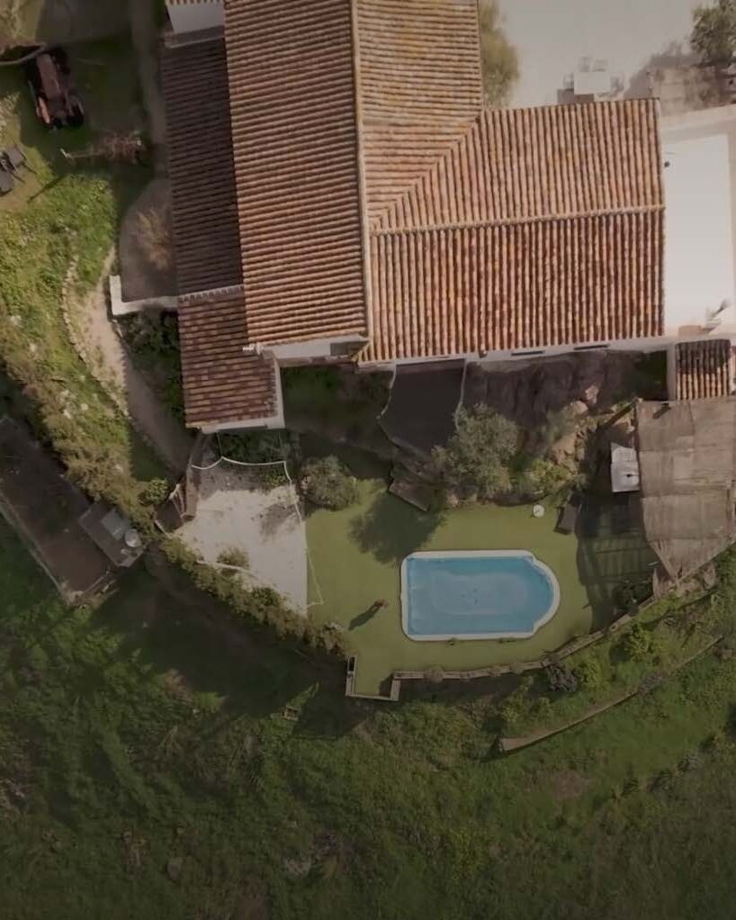 Aerial view of an Andalusian estate: terracotta rooftops, pool and terraced garden cut into the hillside